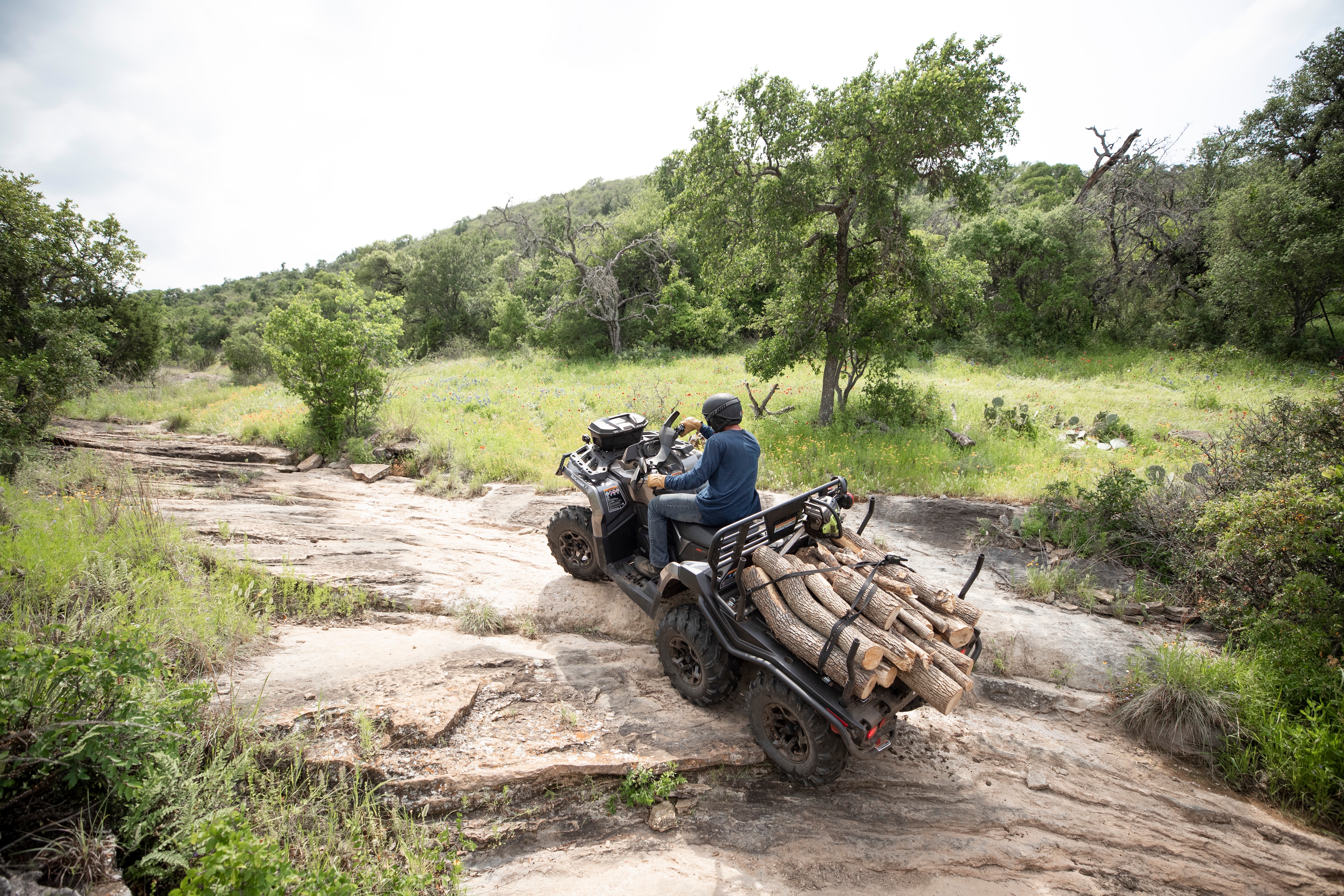 Four ranchers sitting on a cattle fence next to a parked Night Black Can-Am Defender MAX Lonestar CAB